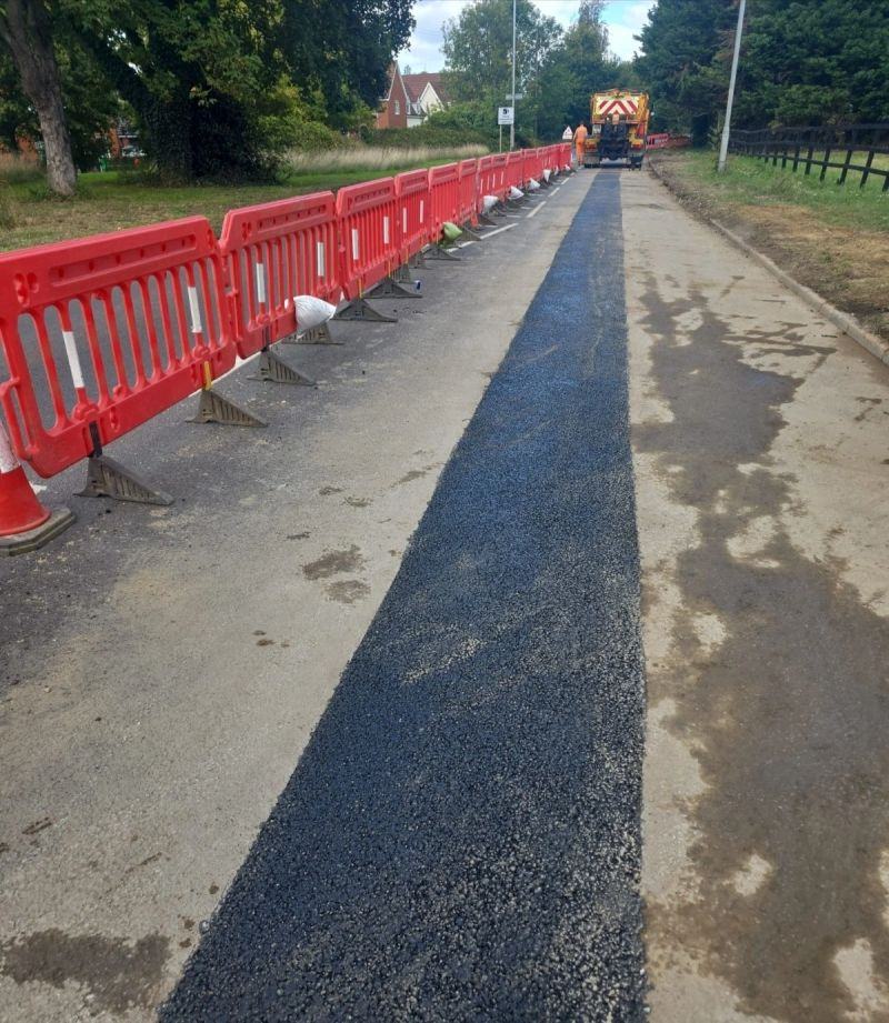 Finished trench reinstatement behind red safety barriers